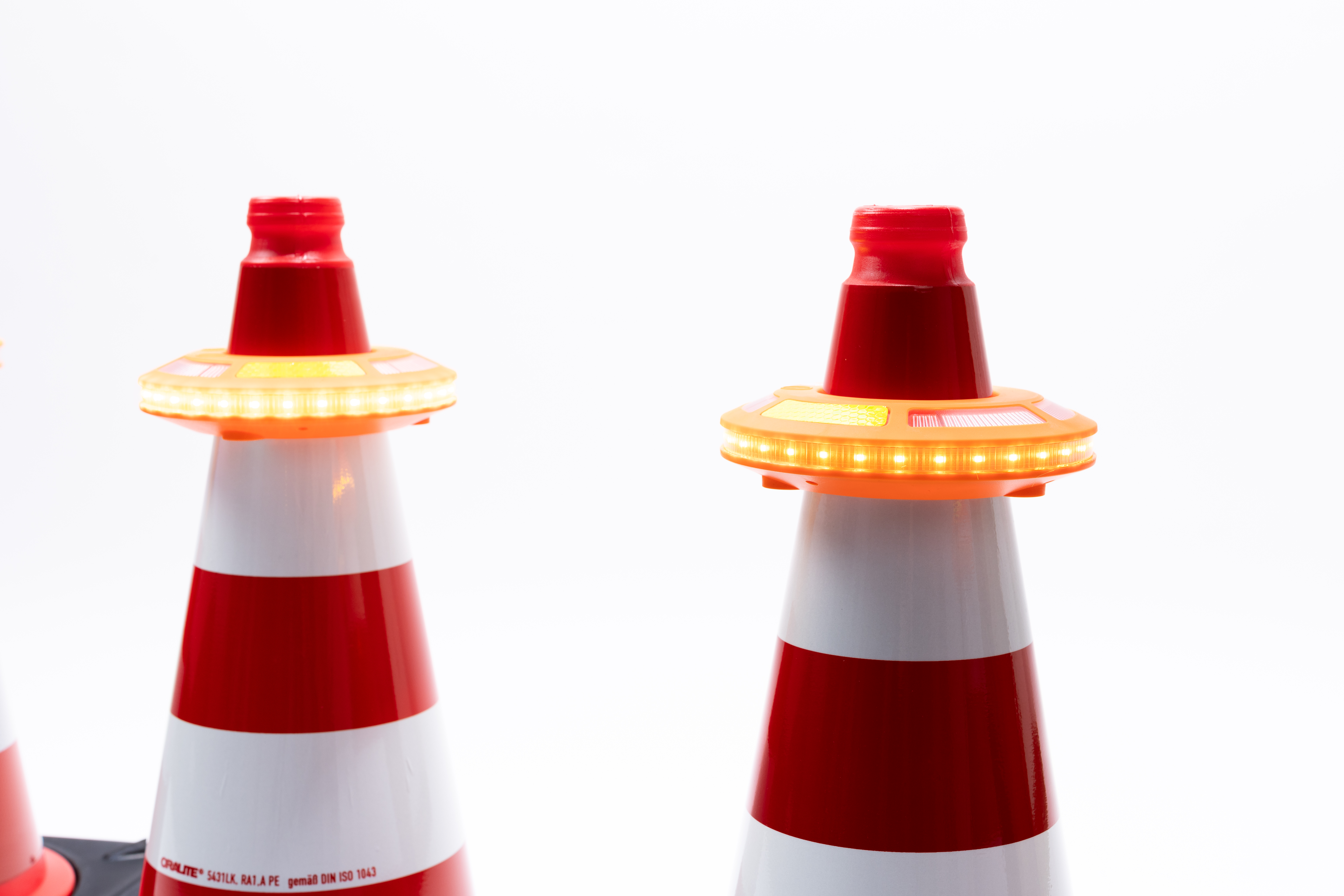 Zwei rot-weiße Leitkegel mit aktivierter LED-Lauflicht im Detail, Vorderansicht