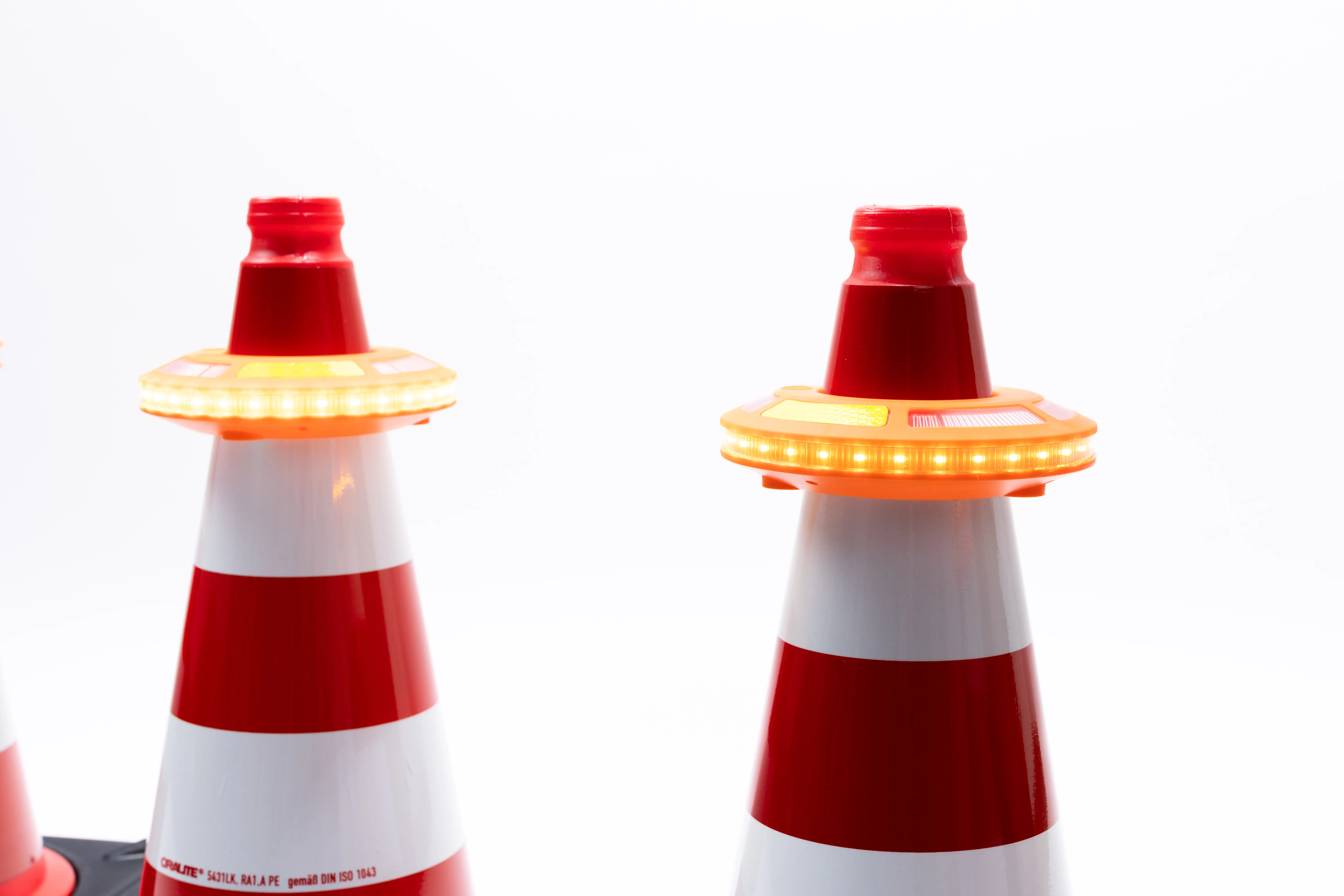 Zwei rot-weiße Leitkegel mit aktivierter LED-Lauflicht im Detail, Vorderansicht