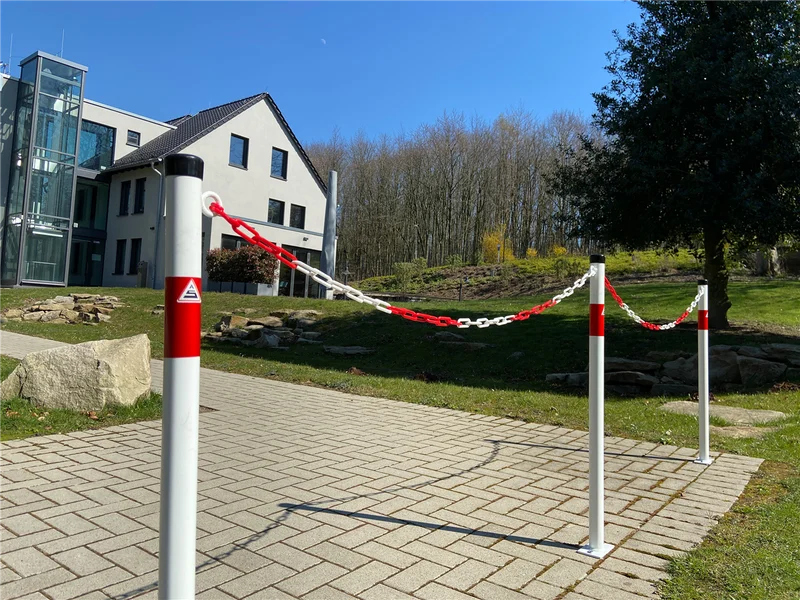 Mehrere montierte Absperrpfosten mit rot-weißer Kunststoffkette zur Flächenabgrenzung im Außenbereich