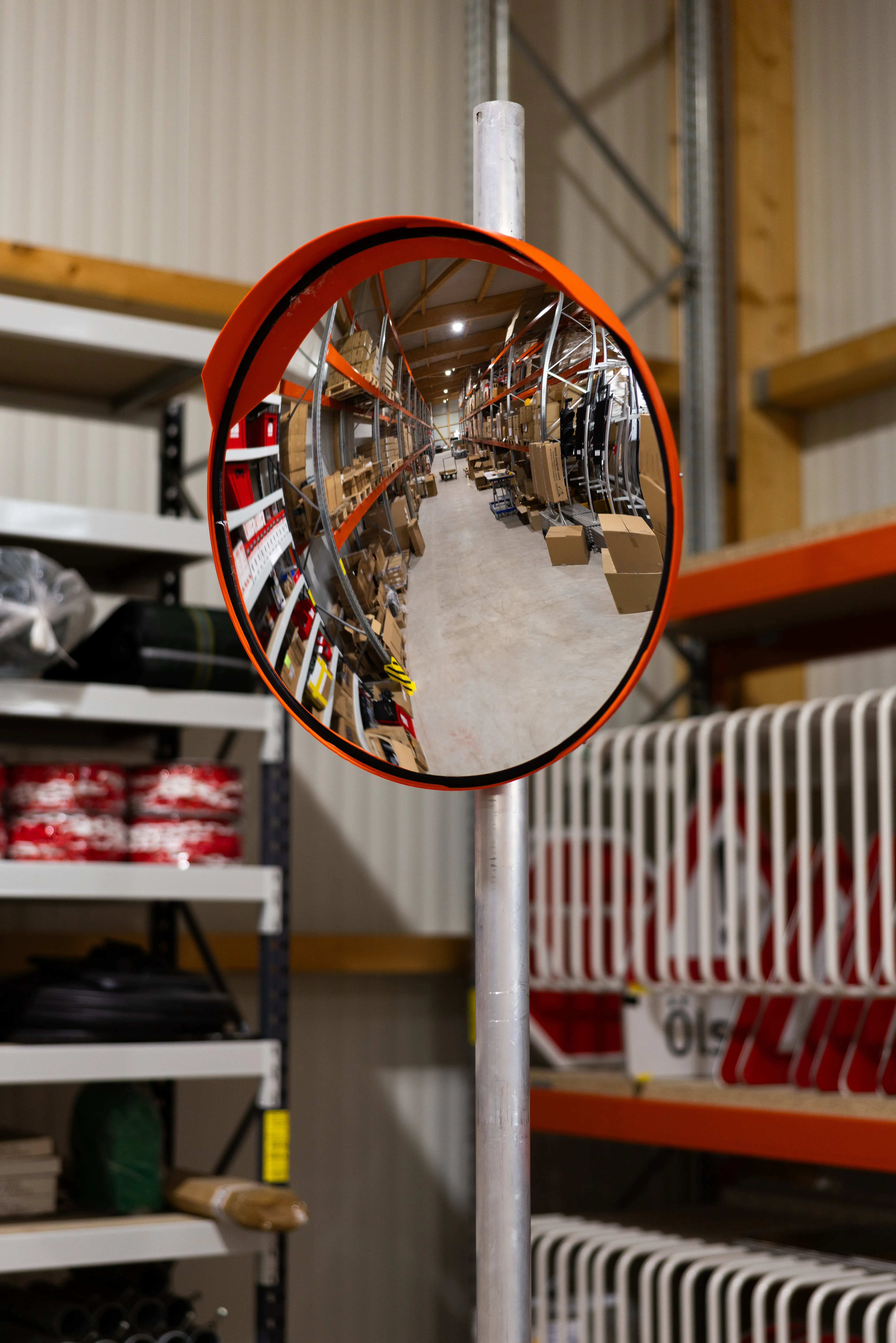  Verkehrsspiegel Iraco mit rotem Rahmen im Innenbereich eines Lagers montiert, Spiegelung zeigt Regale und Kartons