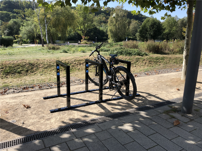 E-Bike Anlehnbügel ohne Ladeeinheit im Außenbereich, montiert auf befestigtem Untergrund, mit abgestelltem Fahrrad
