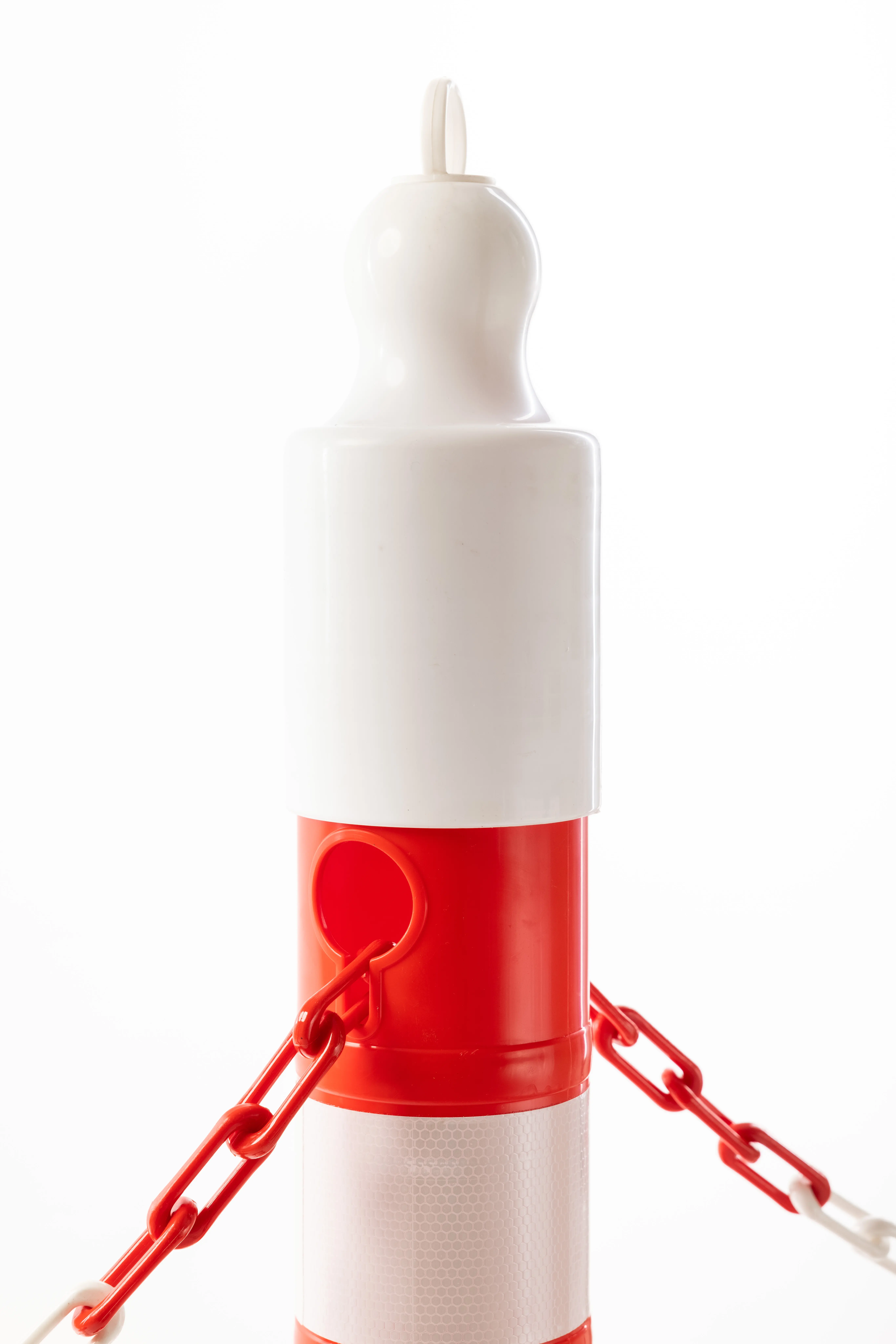 Detailaufnahme eines rot-weißen Absperrpfostens mit roter Kette und weißem Kopfstück mit Aufhängeöse