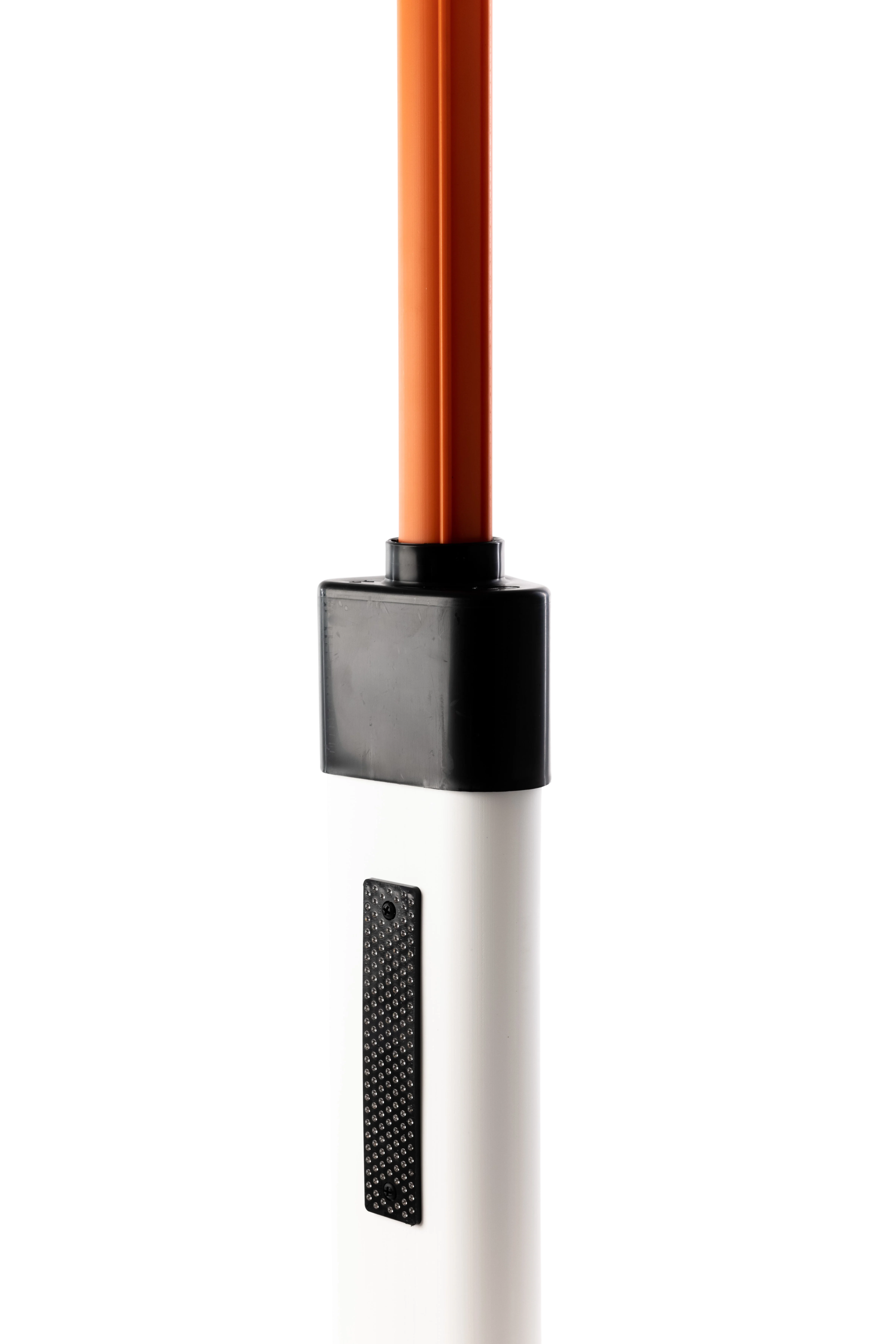 Nahaufnahme eines weißen Leitpflocks mit schwarzer Reflektorfläche und montierter oranger Schneestange