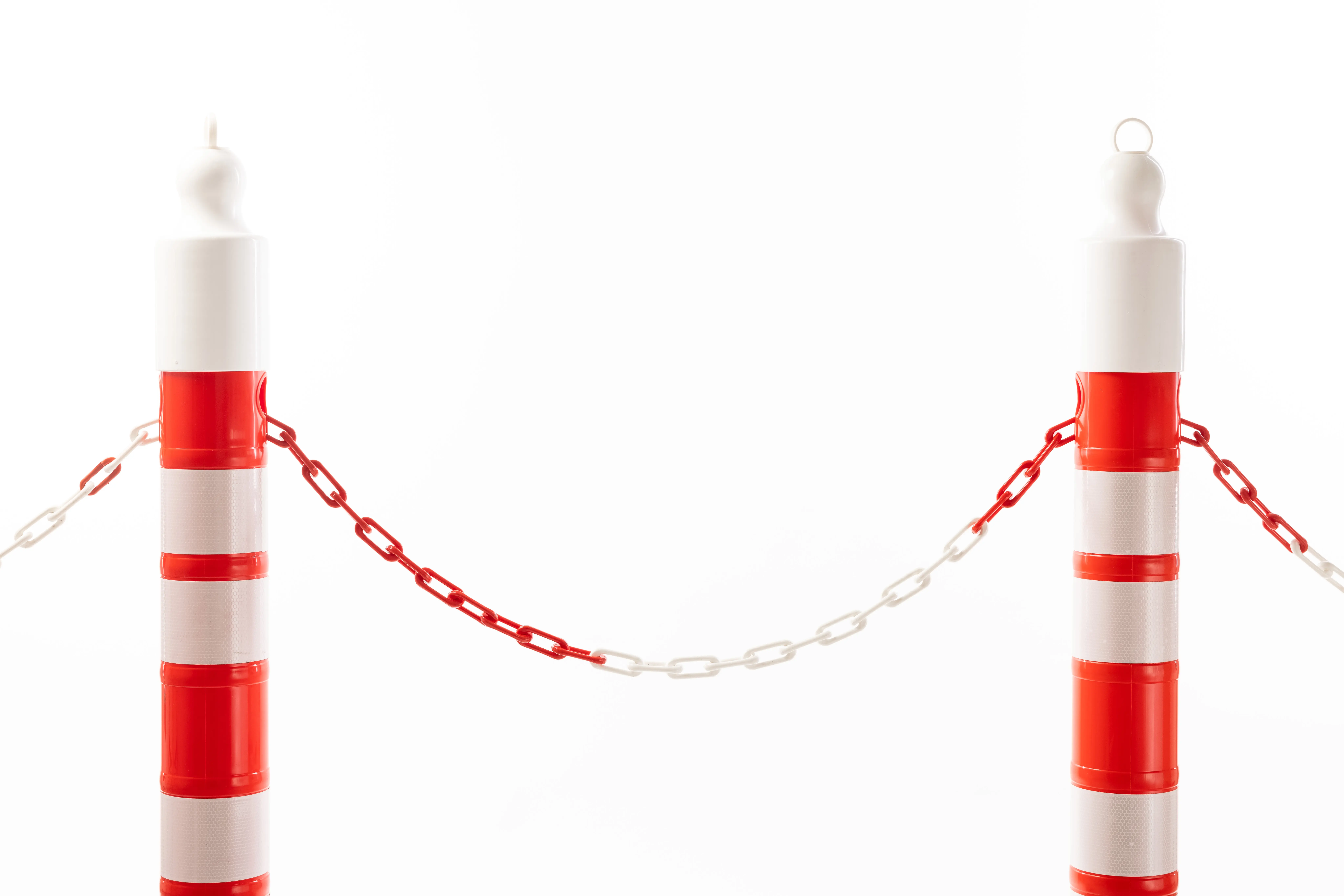 Zwei rot-weiß reflektierende Absperrpfosten mit rot-weißer Kunststoffkette verbunden